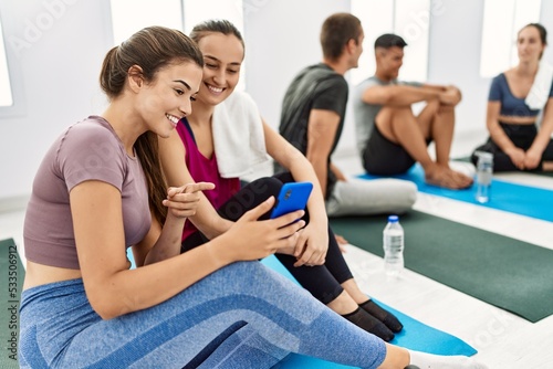 Group of young hispanic people smiling happy relaxing and using smartphone at sport center.
