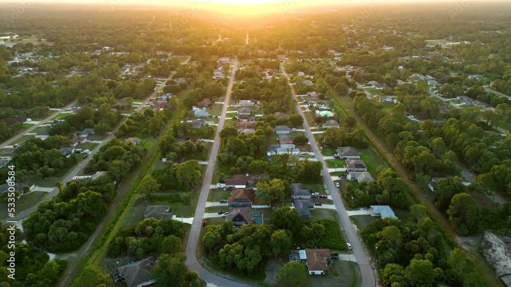 Aerial landscape view of suburban private houses between green palm trees in Florida quiet rural area at sunset