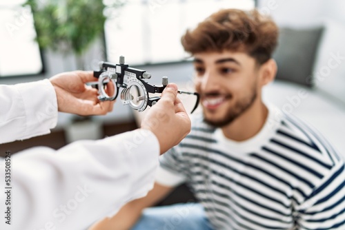 Young arab man smiling confident reciving optometrist glasses at home photo