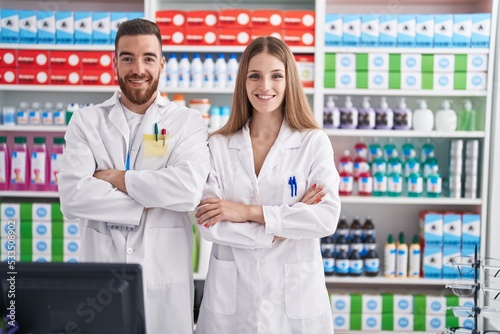 Man and woman pharmacists smiling confident standing with arms crossed gesture at pharmacy photo