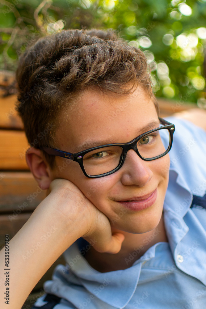 European boy with glasses and curls beams at the camera European boy with glasses and curls beams at the camera