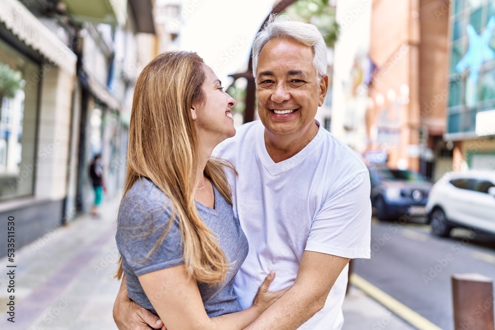 Middle age hispanic couple of husband and wife together on a sunny day outdoors. Smiling happy in love hugging at the city Middle age hispanic couple of husband and wife together on a sunny day outdoors. Smiling happy in love hugging at the city
