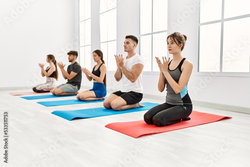 Group of young hispanic people concentrate training yoga at sport center.