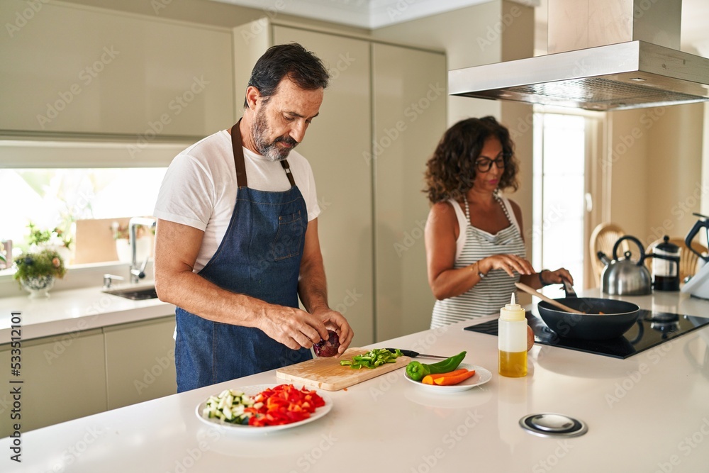 Middle age hispanic couple smiling confident cooking at kitchen