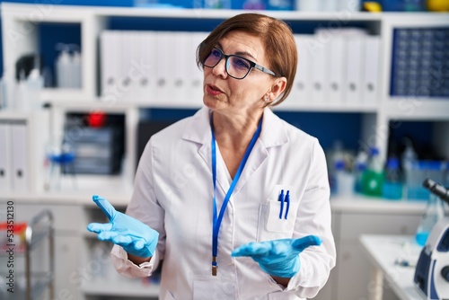 Middle age woman scientist smiling confident speaking at laboratory