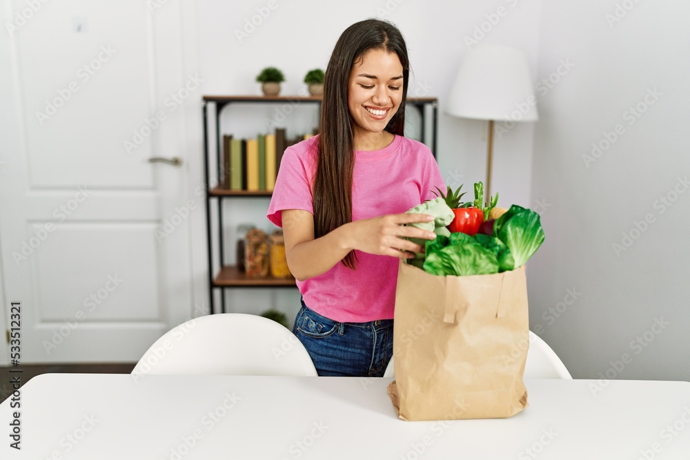 Young latin woman holding food of groceries bag at home Young latin woman holding food of groceries bag at home