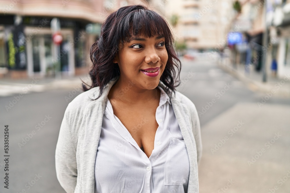Young beautiful latin woman smiling confident looking to the side at street