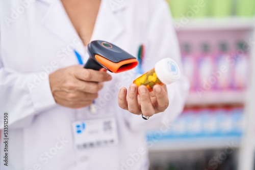 Middle age grey-haired woman pharmacist scanning pills bottle at pharmacy
