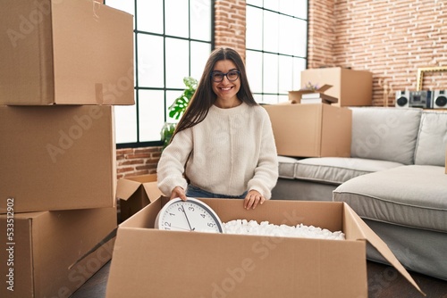 Young hispanic woman smiling confident unpacking cardboard box at new home © Krakenimages.com