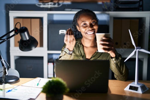 African woman working using computer laptop at night doing money gesture with hands, asking for salary payment, millionaire business