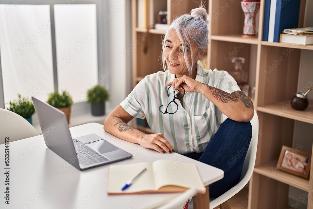 Middle age grey-haired woman smiling confident using laptop at home