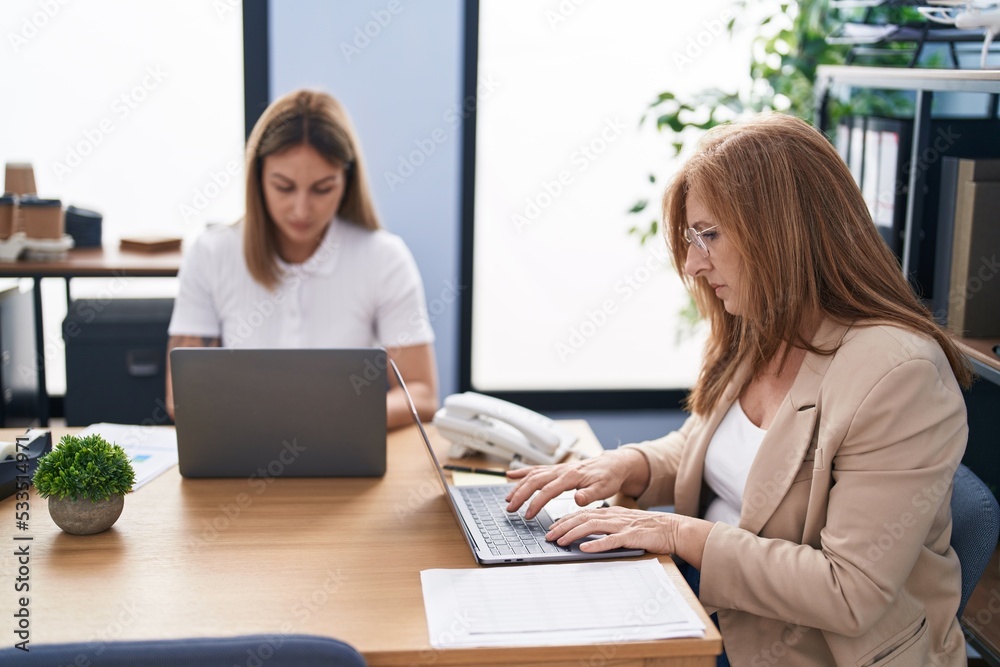 Mother and daughter business workers using laptop working at office Mother and daughter business workers using laptop working at office