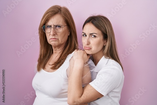 Hispanic mother and daughter wearing casual white t shirt depressed and worry for distress, crying angry and afraid. sad expression.