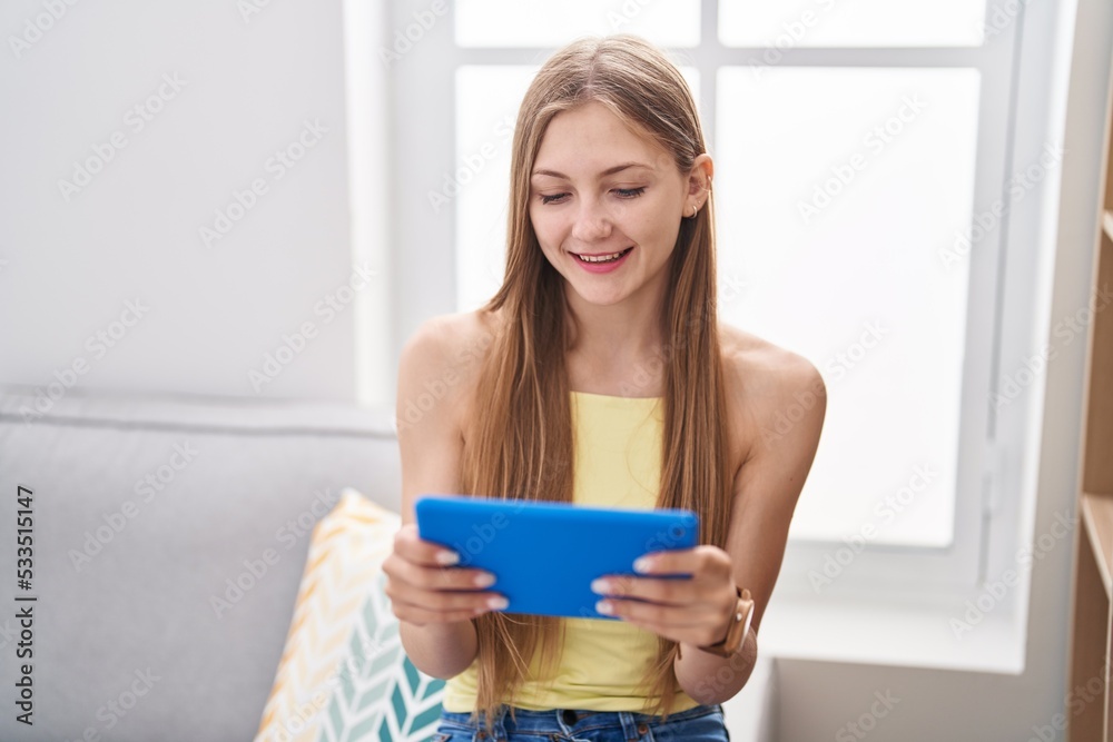 Young caucasian woman using touchpad sitting on sofa at home Young caucasian woman using touchpad sitting on sofa at home