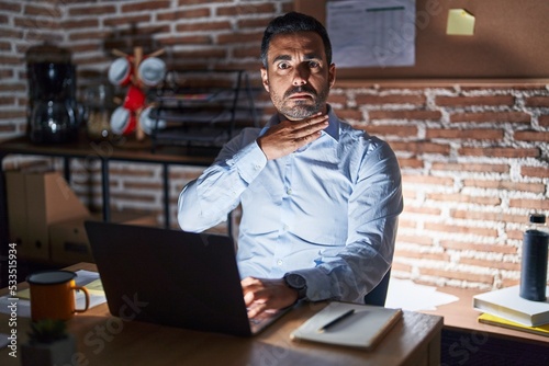 Billede på lærred Hispanic man with beard working at the office at night cutting throat with hand