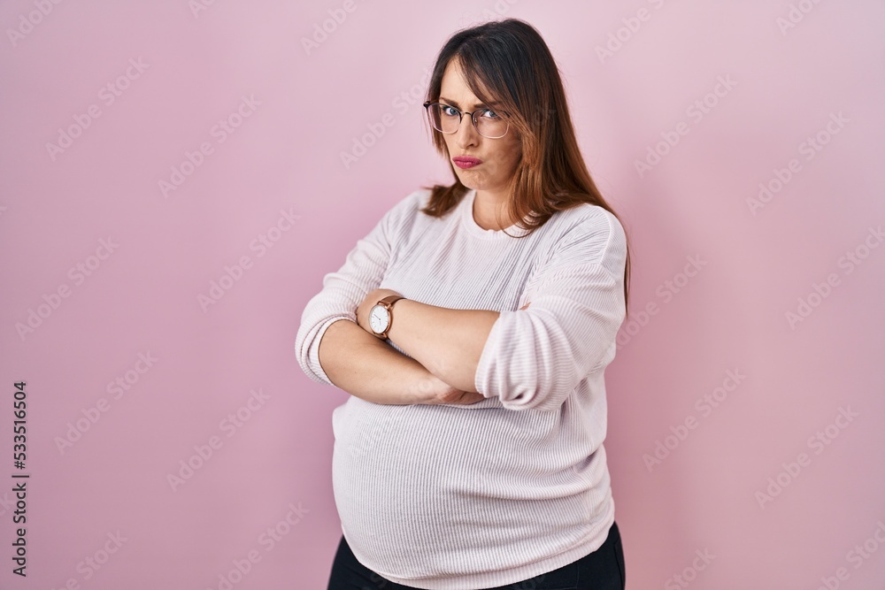 Pregnant woman standing over pink background skeptic and nervous, disapproving expression on face with crossed arms. negative person. Pregnant woman standing over pink background skeptic and nervous, disapproving expression on face with crossed arms. negative person.