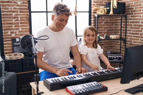 Father and daughter playing piano keyboard at music studio