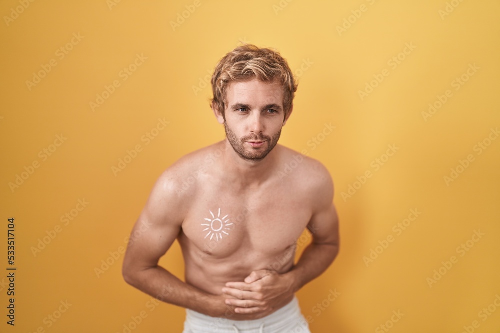Caucasian man standing shirtless wearing sun screen with hand on stomach because indigestion, painful illness feeling unwell. ache concept.