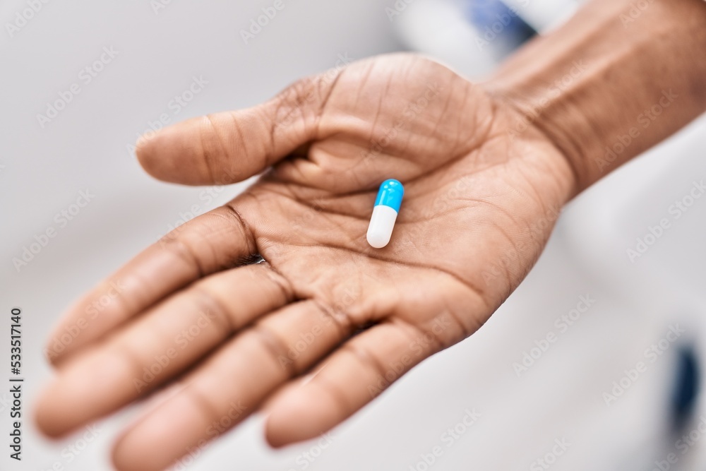 African american woman hand holding pill at clinic African american woman hand holding pill at clinic