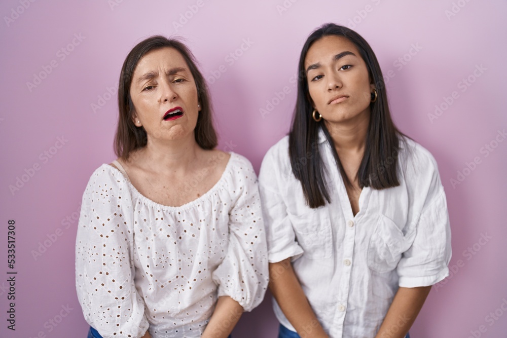Hispanic mother and daughter together looking sleepy and tired, exhausted for fatigue and hangover, lazy eyes in the morning. Hispanic mother and daughter together looking sleepy and tired, exhausted for fatigue and hangover, lazy eyes in the morning.