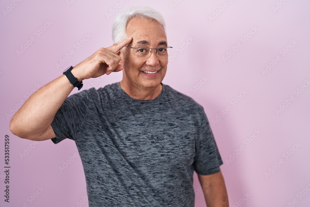 Middle age man with grey hair standing over pink background smiling pointing to head with one finger, great idea or thought, good memory Middle age man with grey hair standing over pink background smiling pointing to head with one finger, great idea or thought, good memory