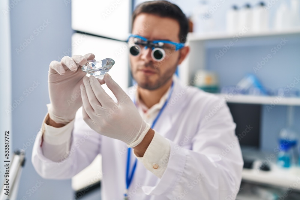 Young hispanic man scientist looking diamond by magnifying glasses at laboratory Young hispanic man scientist looking diamond by magnifying glasses at laboratory