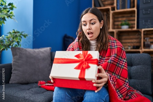 Young hispanic woman opening gift box in shock face, looking skeptical and sarcastic, surprised with open mouth © Krakenimages.com