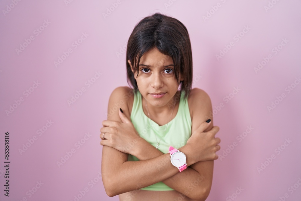 Young girl standing over pink background shaking and freezing for winter cold with sad and shock expression on face Young girl standing over pink background shaking and freezing for winter cold with sad and shock expression on face