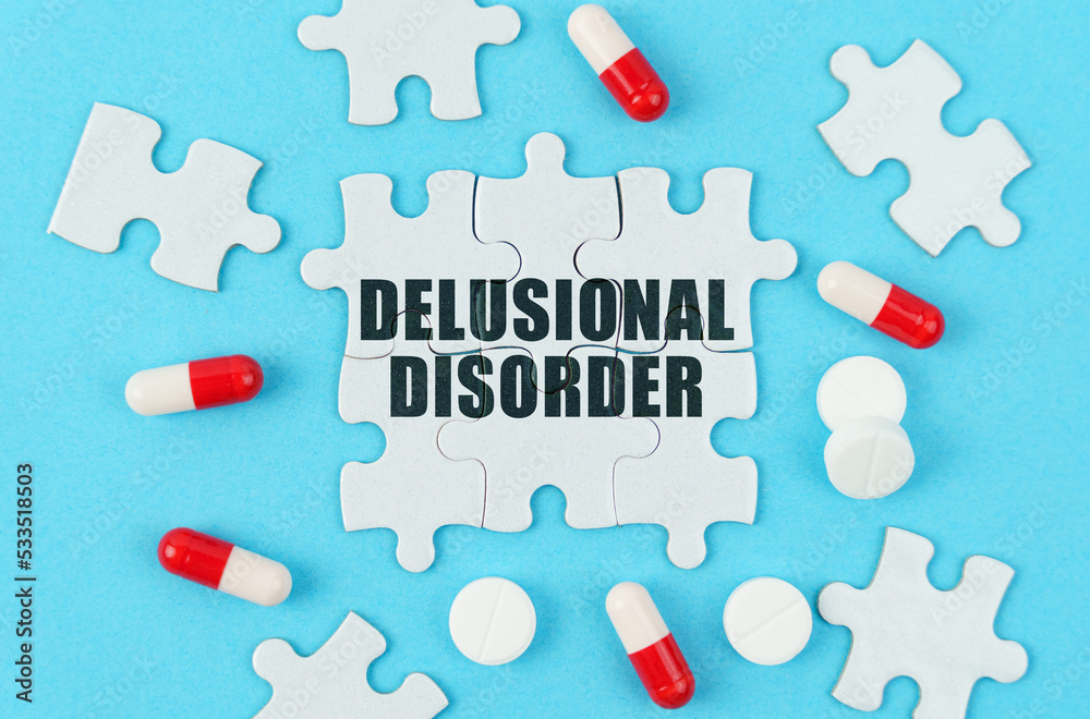 On a blue background, pills, capsules and puzzles with the inscription - Delusional disorder On a blue background, pills, capsules and puzzles with the inscription - Delusional disorder