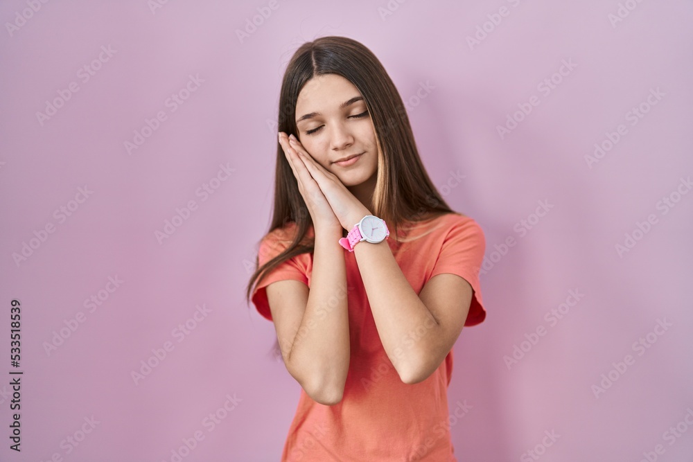 Teenager girl standing over pink background sleeping tired dreaming and posing with hands together while smiling with closed eyes. Teenager girl standing over pink background sleeping tired dreaming and posing with hands together while smiling with closed eyes.