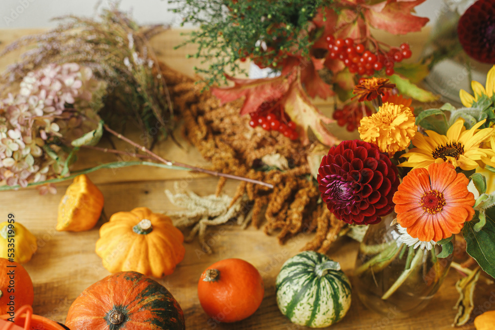 Autumn flowers, pumpkins, berries on rustic wooden table. Autumn still life. Harvesting at farm. Hello Fall