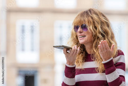 middle aged woman on the street with mobile phone sending voice message