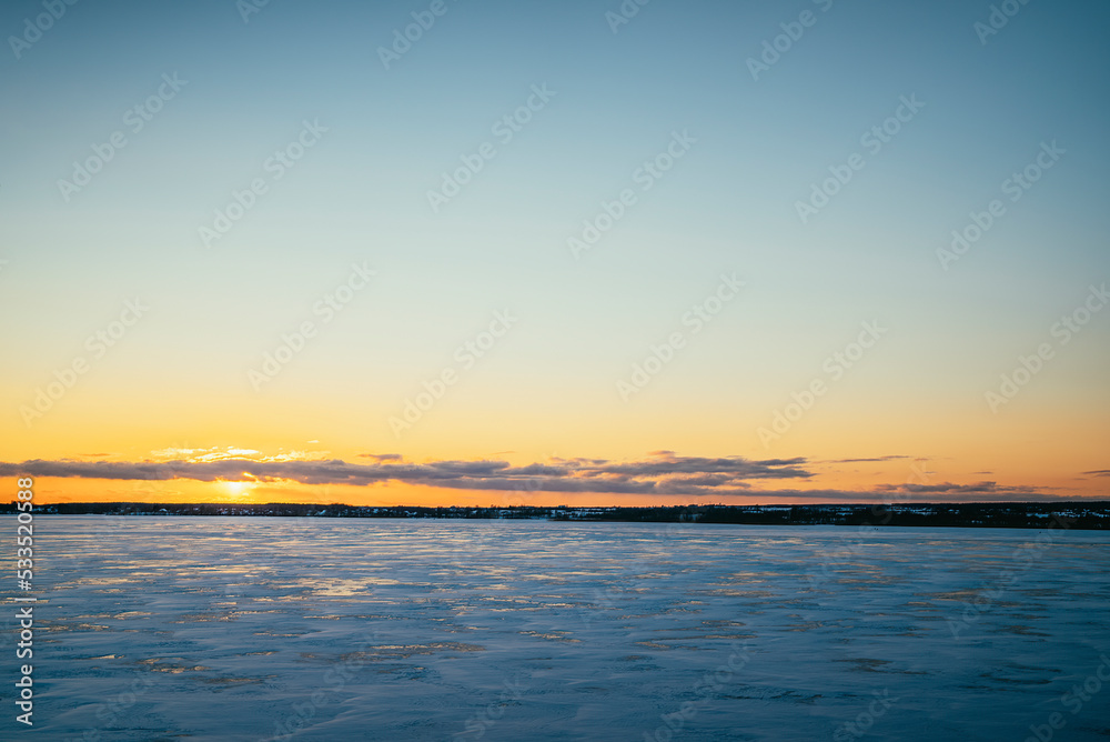 landscape at sunset frozen lake covered with snow in winter on a cold day