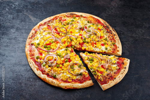 Traditional Italian pizza Mexico with corn, beans and paprika served as close-up on an old rustic board with text free space