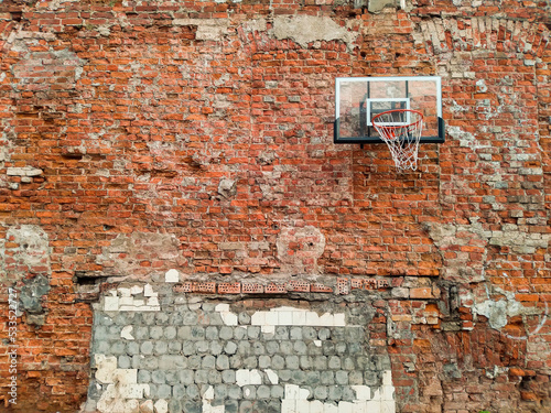 Old and worn outdoor basketball hoop net on the red brick wall background, Urban playground, Downtown in the City