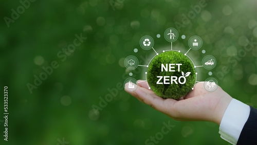 Net zero icon and carbon neutral concept in the hand for net zero greenhouse gas emissions target Climate neutral long term strategy on a green background.