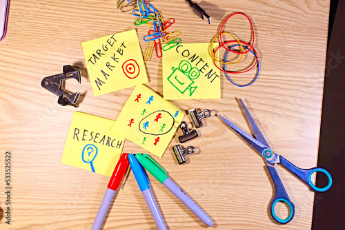 Niche target audience marketing research concept. Stationary flat lay with sticky notes, felt tip pens, paperclips, elastic bands. Market segmentation. Content creation. Target audience. Wooden table.