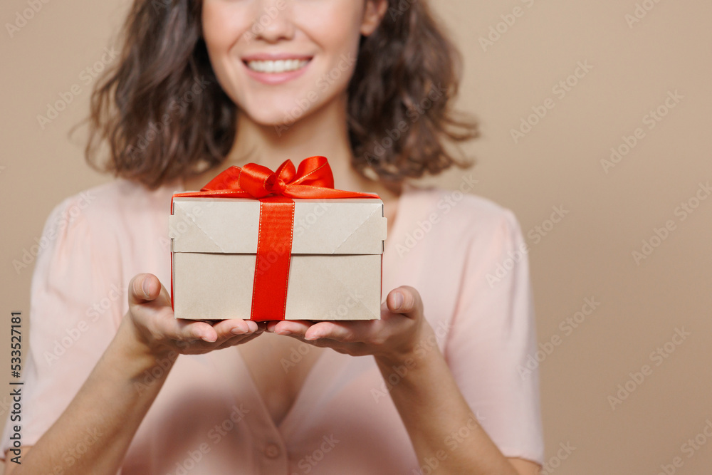 woman is holding a box with a gift for Christmas or birthday on a beige background, a surprise. a beautiful Italian woman smiles and congratulates on the holiday. sale, poster for a cosmetics or woman is holding a box with a gift for Christmas or birthday on a beige background, a surprise. a beautiful Italian woman smiles and congratulates on the holiday. sale, poster for a cosmetics or