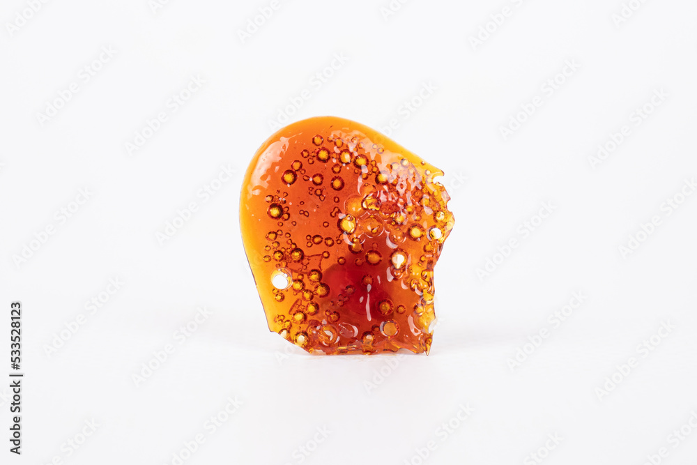 golden isolated piece of cannabis wax, shatter dab closeup golden isolated piece of cannabis wax, shatter dab closeup