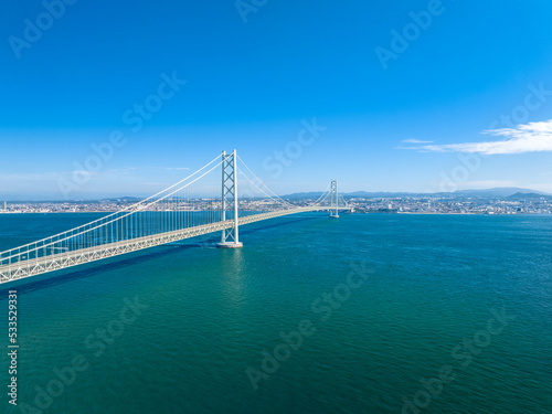 Long suspension bridge over calm water on sunny blue sky day