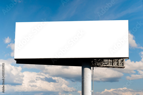 Mock up - blank wide horizontal white billboard or large advertising display against blue sky with white clouds. Consumerism, white screen, template, mock up and copy space concept