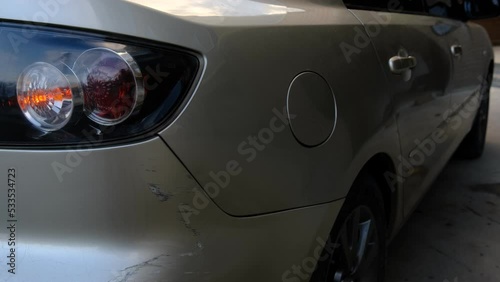 Scratch abrasion on car back bumper due to minor accident with flashing emergency yellow lights.