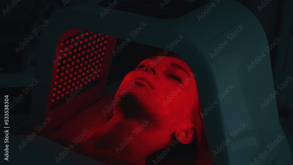 LED red light is treating the facial skin of a young woman.