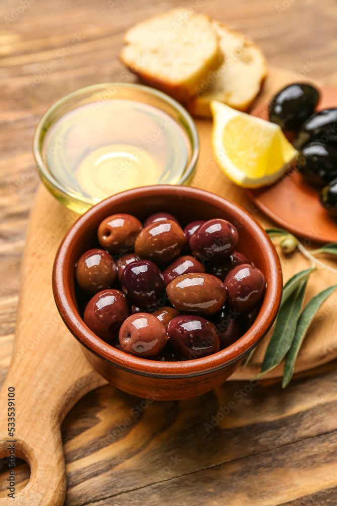 Board with bowls of delicious olives and oil on wooden table, closeup Board with bowls of delicious olives and oil on wooden table, closeup