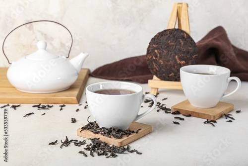 Stands with cups of puer tea and teapot on white background