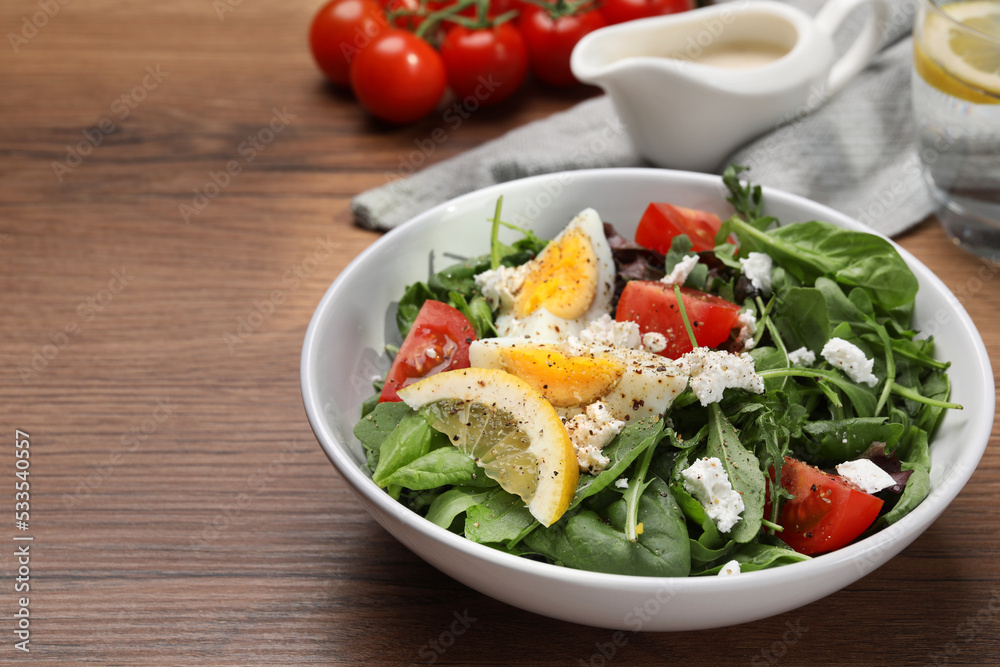 Delicious salad with boiled egg, tomatoes and cheese in bowl on wooden table, closeup. Space for text Delicious salad with boiled egg, tomatoes and cheese in bowl on wooden table, closeup. Space for text