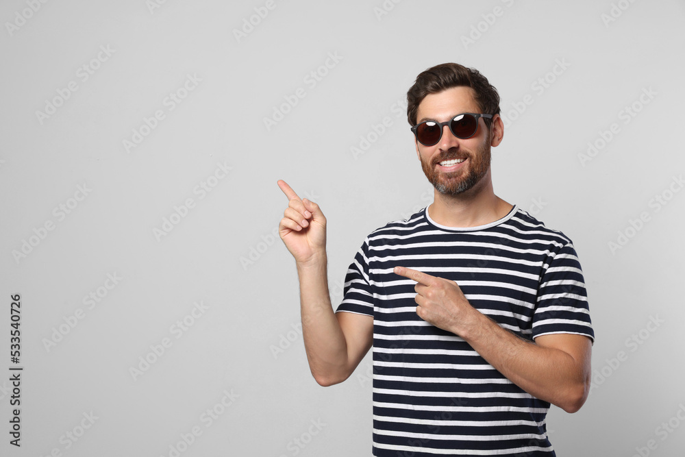 Portrait of smiling bearded man with stylish sunglasses on light grey background. Space for text Portrait of smiling bearded man with stylish sunglasses on light grey background. Space for text