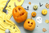 Carved Halloween pumpkins with decor on grey wooden background
