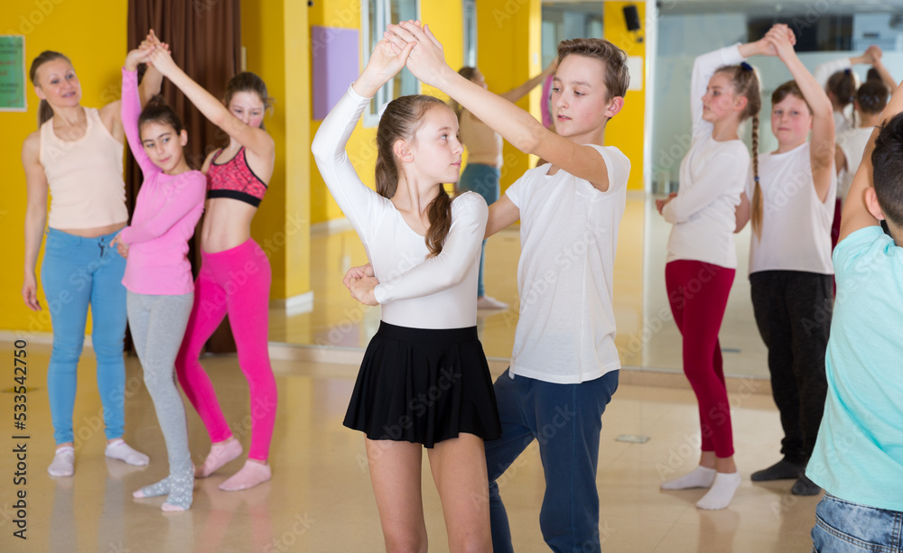 Children dancing rock-and-roll in pairs in choreography class with female trainer