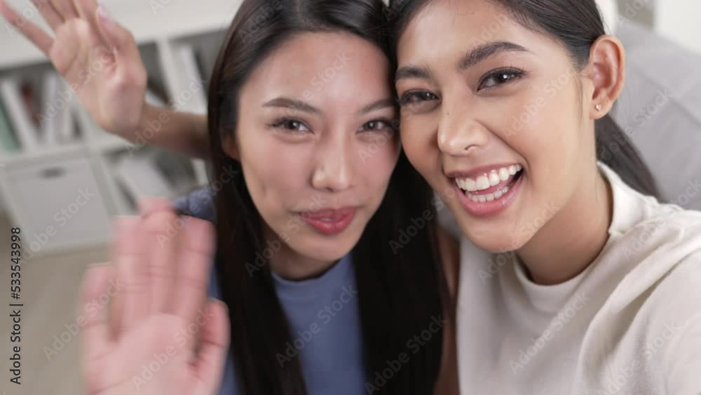 Young Asian lesbian couple video call to their friends and family with smartphone. Young Asian lesbian couple video call to their friends and family with smartphone.